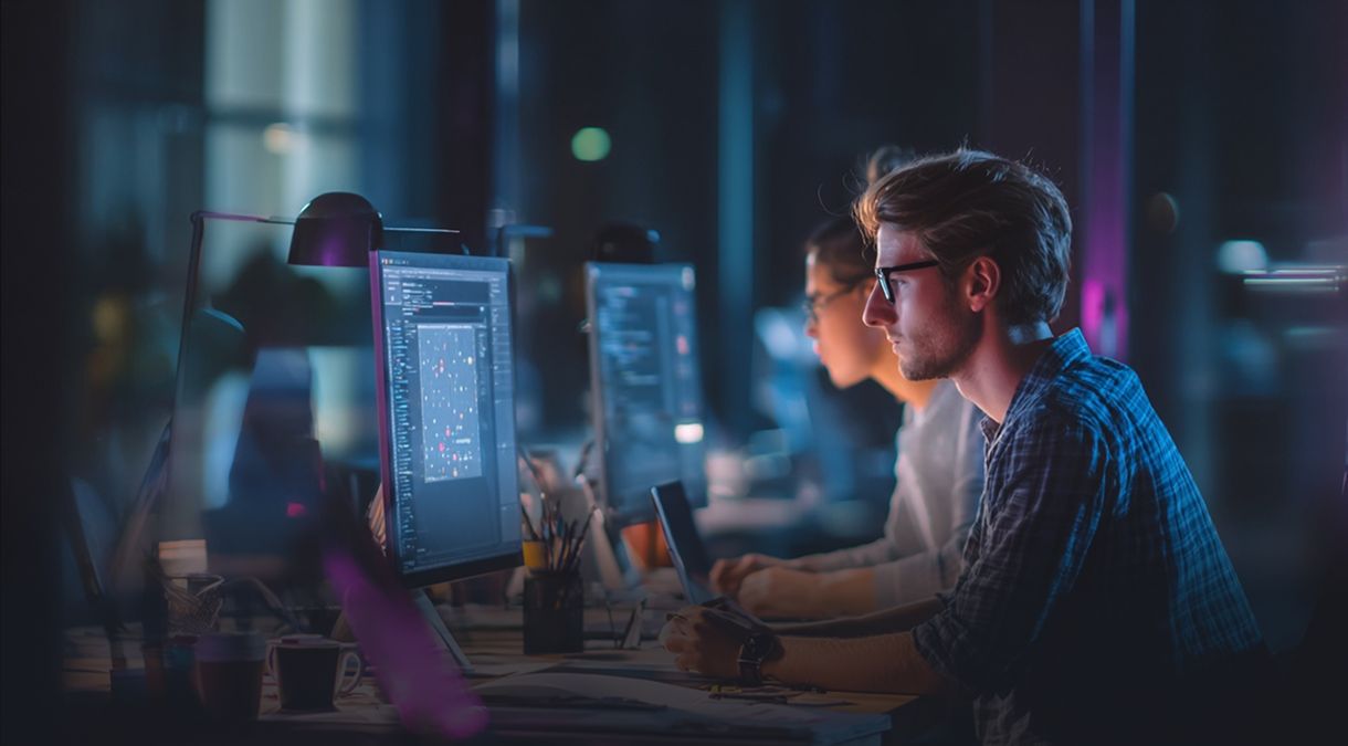 Equipo de desarrollo de Wigilabs trabajando de noche entre monitores