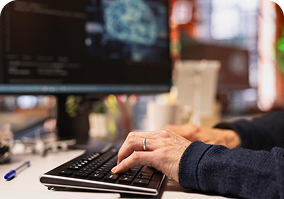Hands typing on a keyboard in front of a monitor